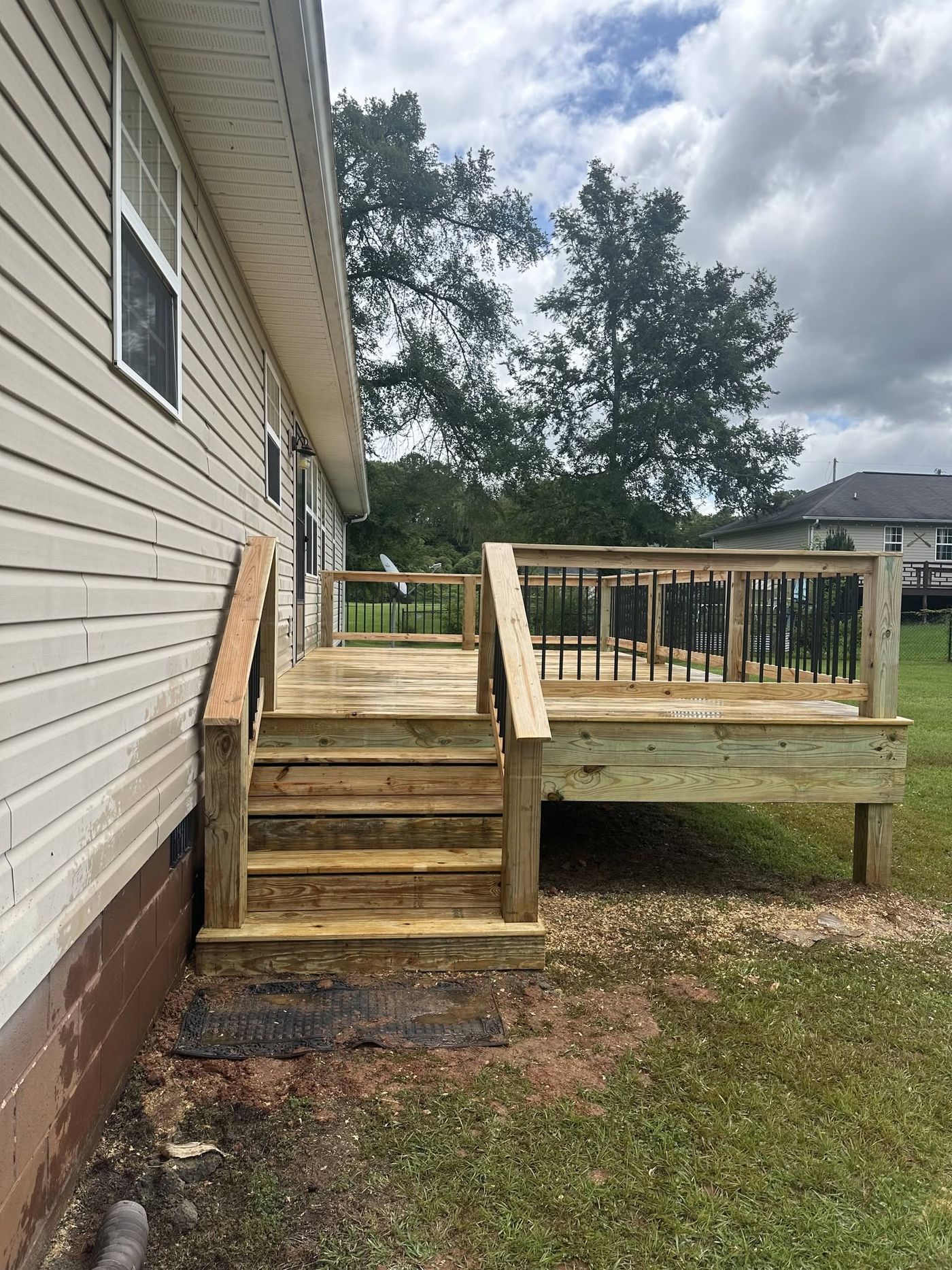New backyard deck with black metal balusters and side stairs