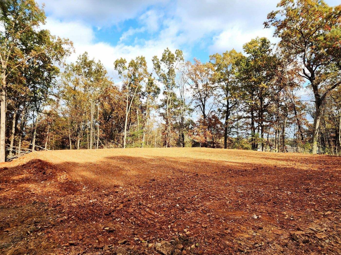 Cleared and graded building spot surrounded by fall trees