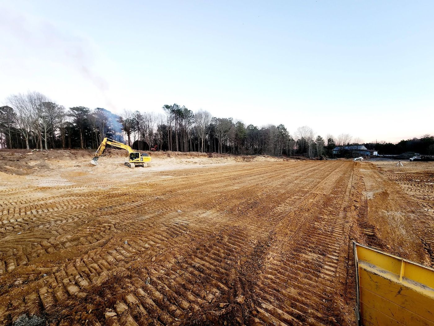 Large commercial site rough-graded with excavator working the back cut