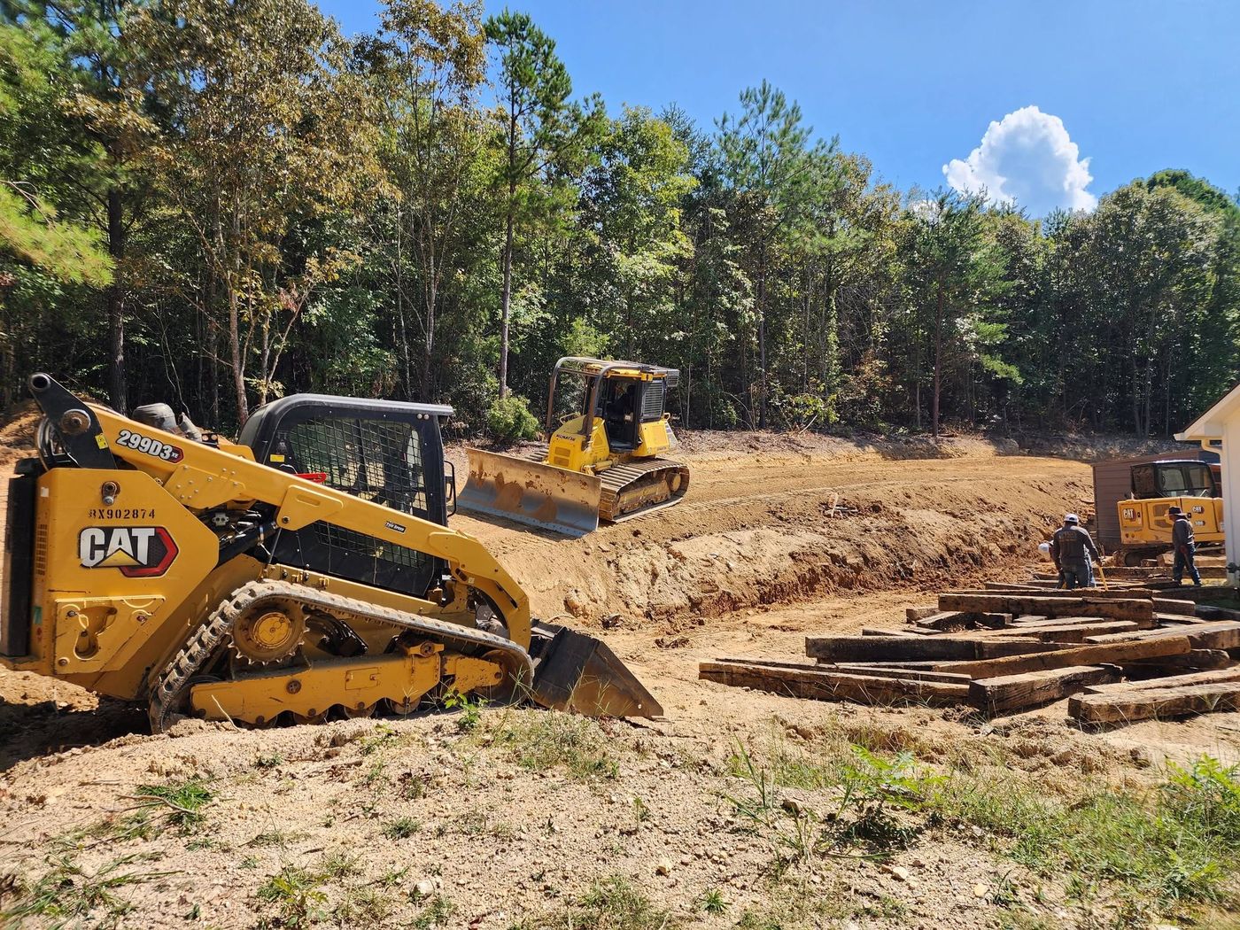 Pack's crew setting timbers for a retaining wall with dozer and skid steer on site