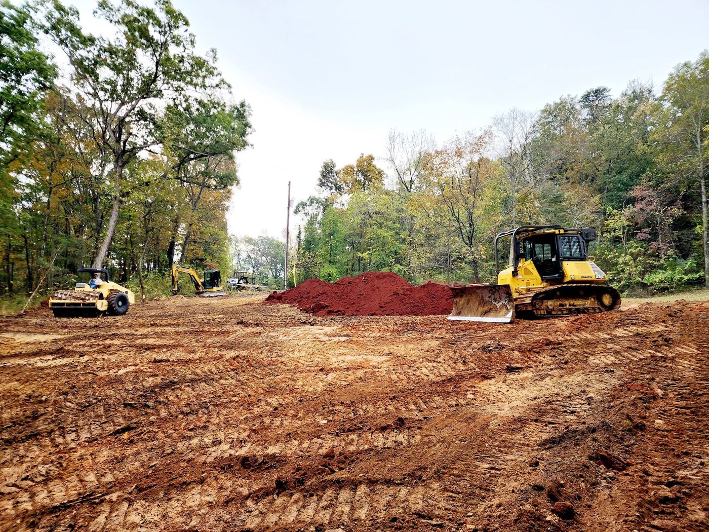 Dozer and roller working fresh fill dirt piles