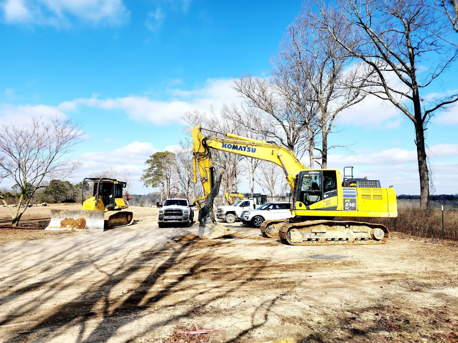 Komatsu excavator and dozer staged with support trucks