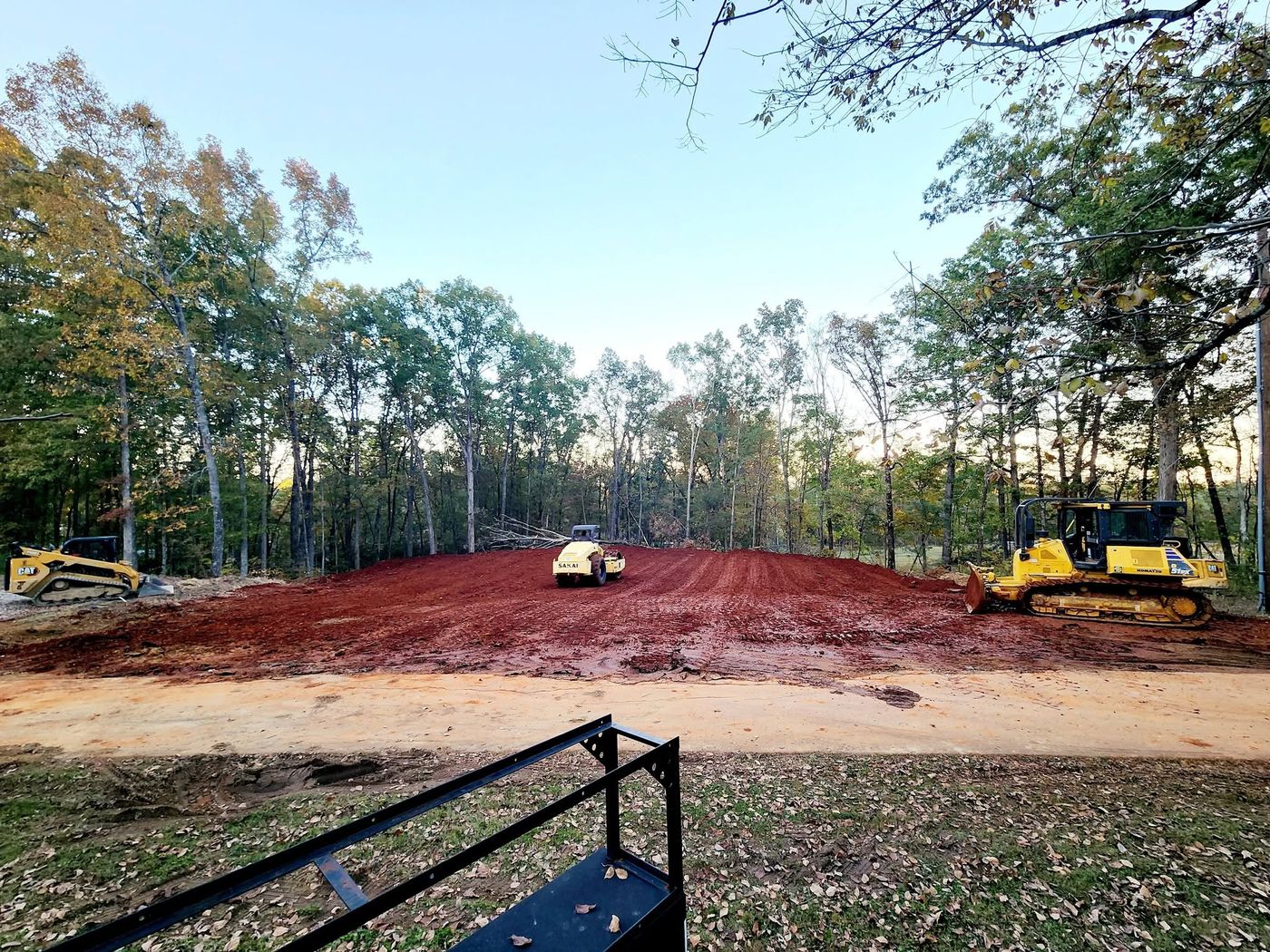 Roller compacting a red clay house pad prepared by Pack's