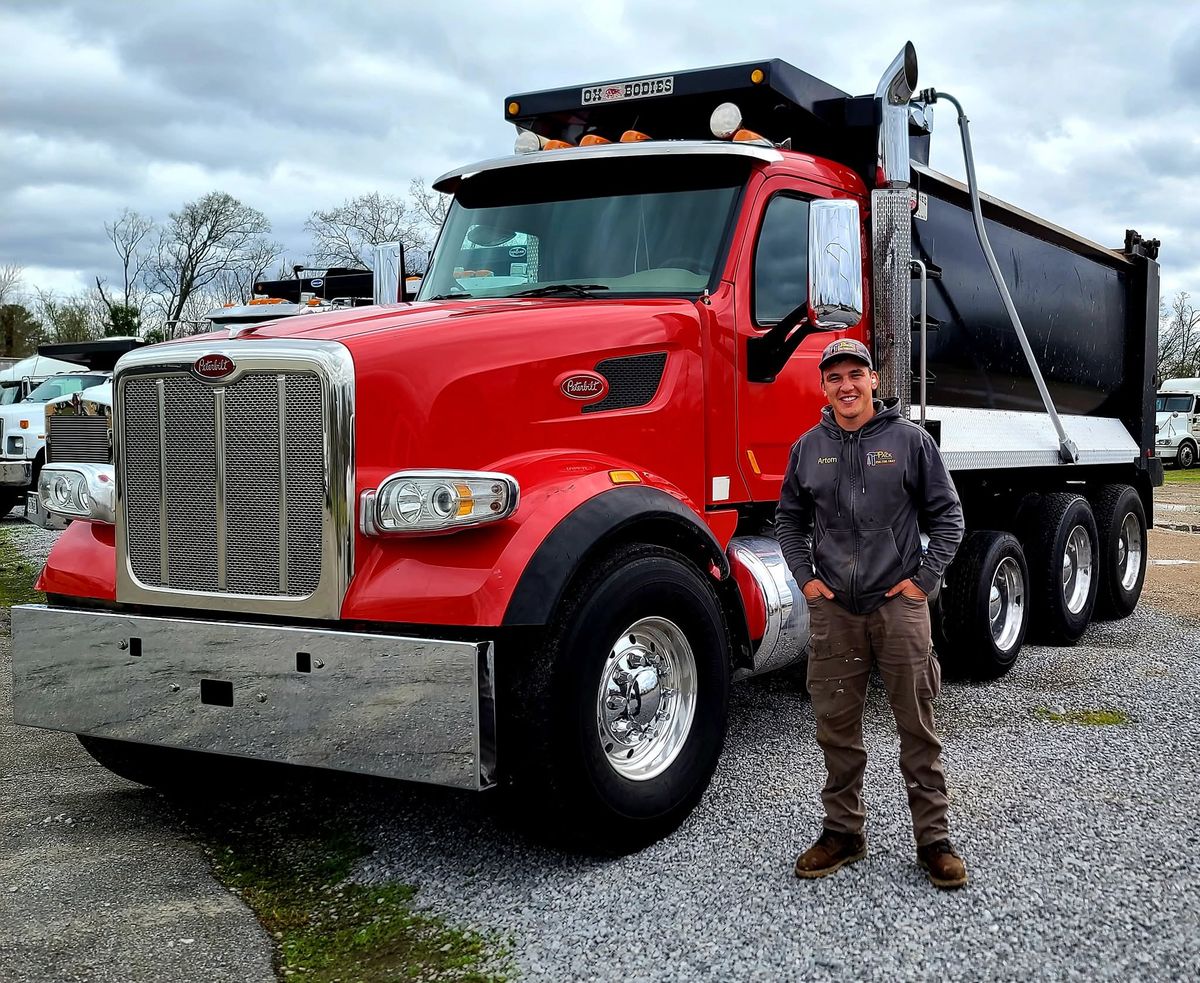 Artom Pack, owner of Pack's Construction and Landscaping, standing beside a company dump truck