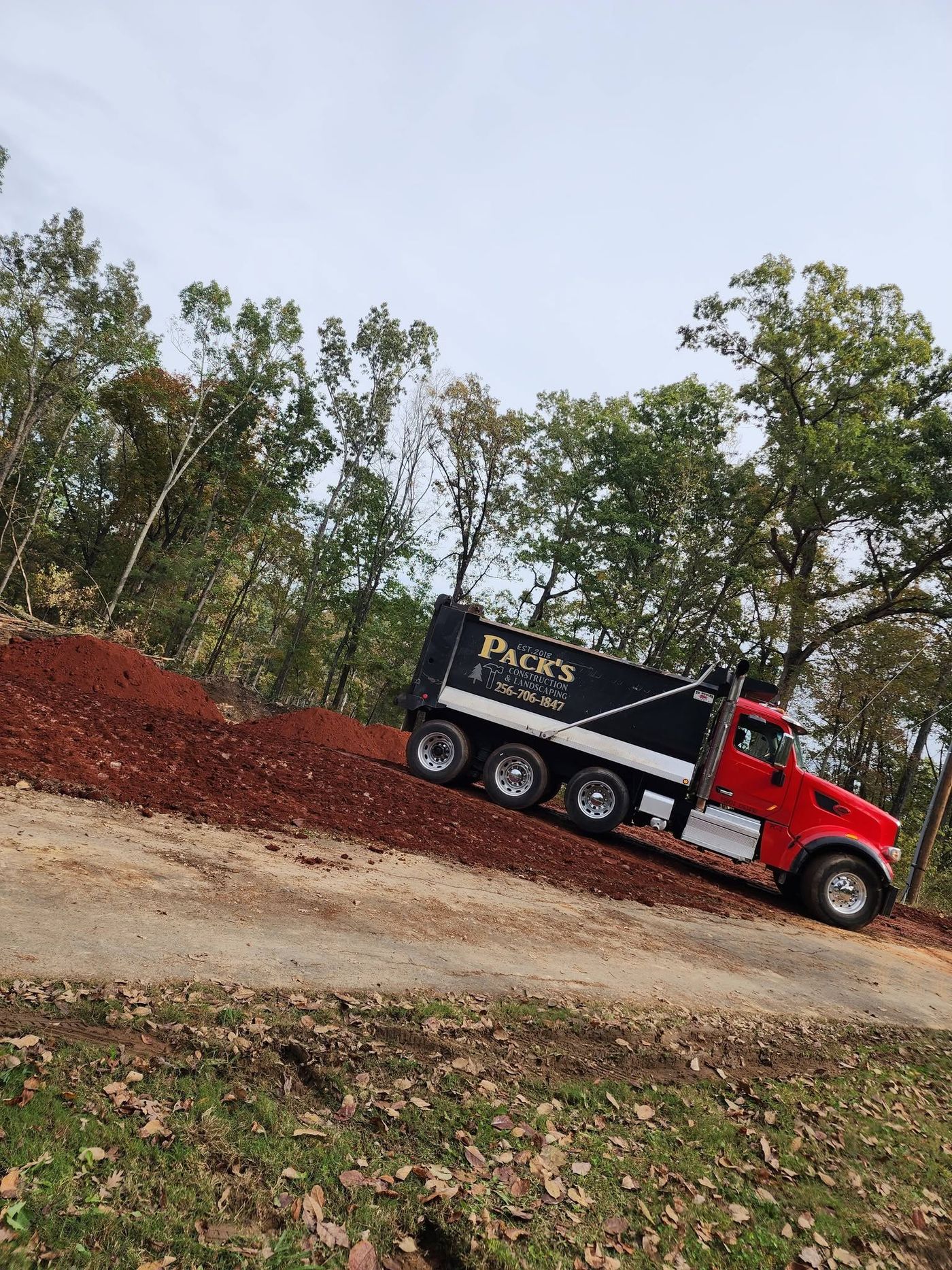 Pack's dump truck delivering fill dirt to a job site