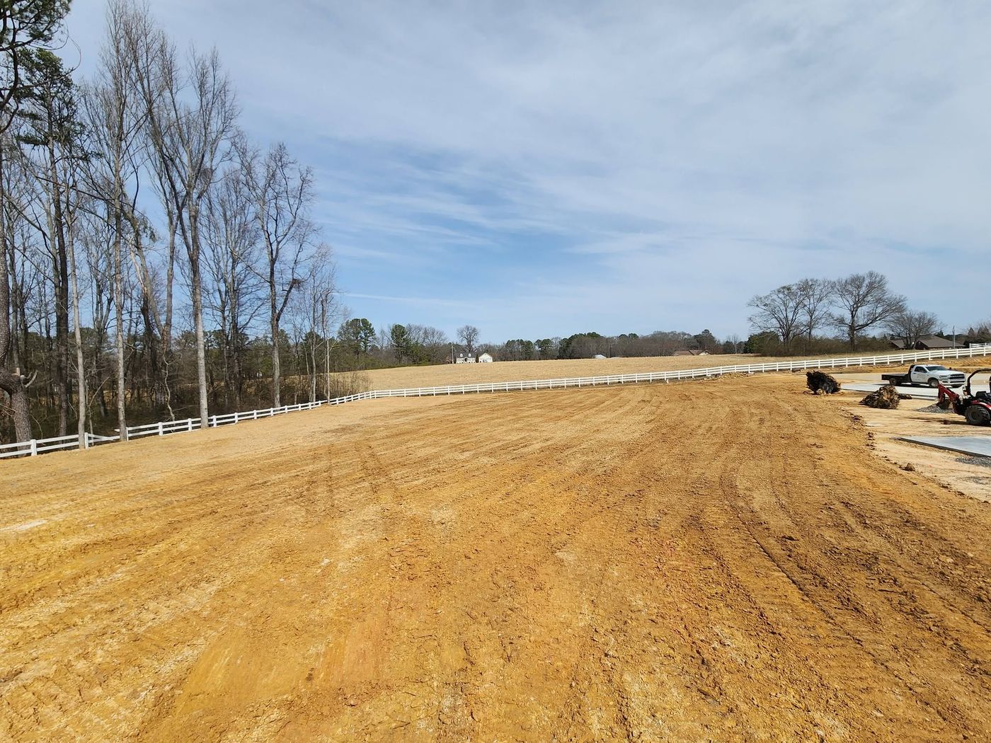 Pasture graded along a white board fence